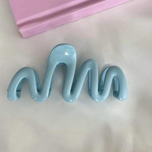 Detail showing high-gloss light blue wavy hair claw clip with interlocking teeth