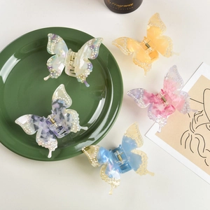 Close-up of five acetate butterfly hair clips with pearl details in various colors