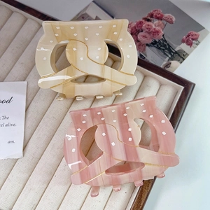 Detail of cream and pink acetate hair claws with marble texture and white polka dots decoration