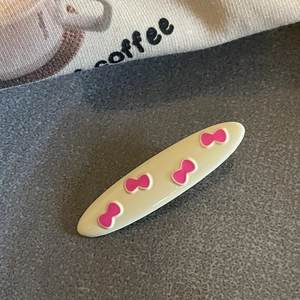 Detail of cream oval hair clip with pink bow pattern and alloy oil drip texture