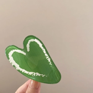 Detailed view of a green heart-shaped hair claw clip with white graffiti patterns