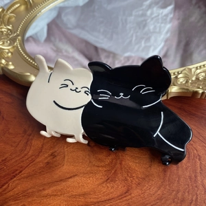 Cute black and white acetate cat hair claw clip on vintage background, 80-100 chars.