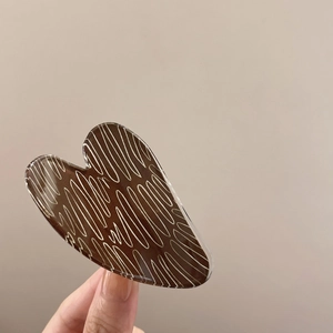Detail showing the brown acrylic heart hair claw clip with white artistic marble texture