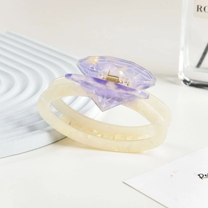 Detail view of a cream oval hair claw clip with a purple diamond-cut acetate ornament
