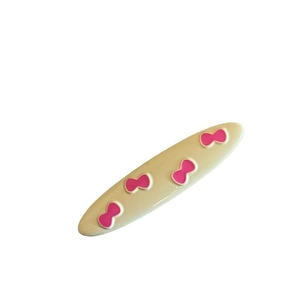 Minimalist beige resin hair clip featuring decorative pink bow patterns and a glossy finish