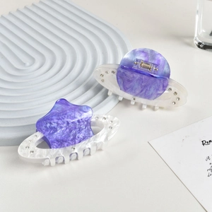 Close-up of marble acetate hair claws with sparkling rhinestones in star and round shapes