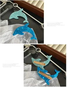 Detail of dolphin hair clips in blue marbled acetate with gold duckbill fasteners