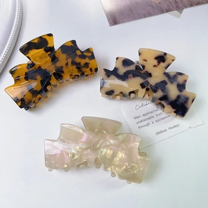 Three acetate bow claw clips in tortoise, floral, and pearl finishes for women