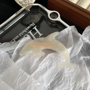 Detail of dolphin-shaped hair clip with iridescent pearl finish and acetate material