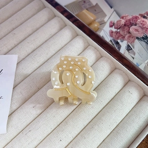 Macro shot of beige acetate hair claw clip with polka dots and gold glitter spiral patterns