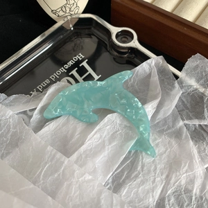 Detail of dolphin hair clip featuring light blue faux acetate with icy stone texture