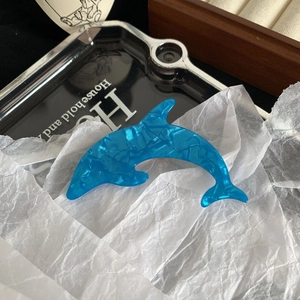 Detail view of a bright blue dolphin hair clip with a fine water ripple texture finish