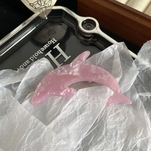 Detail of pink dolphin-shaped hair clip with pearlescent marble texture acetate material