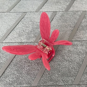 Detailed macro view of a pink butterfly hair claw with resin finish and golden spring