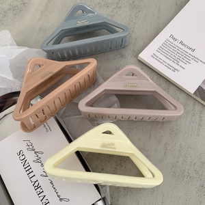 Detailed close-up of matte geometric triangle hair claws in macaron colors and brand text