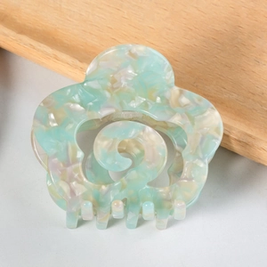 Close-up of floral acetate hair claw clip with mint green marble texture and hollow center