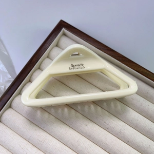 Detail view of cream triangle hair claw clip on wooden jewelry box showing internal teeth