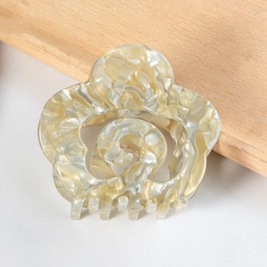Macro detail of cream marble texture on a hollow acetate flower hair claw clip