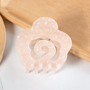 Detailed close-up of a pink acetate flower hair claw clip with marble texture and metal spring