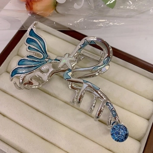 Macro detail of silver mermaid tail hair claw with blue enamel and starfish accents