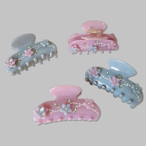 Detail of large acetate hair claws with rhinestones and 3D floral designs in pink and blue