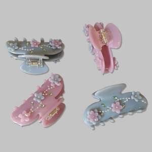 Close-up of floral acetate hair claws with sparkling rhinestones in pink and grey-blue