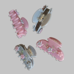 Detail of acetate flower hair claws in pink and blue with rhinestones and matte floral motifs
