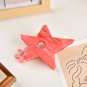 Détail de la pince à cheveux étoile effet marbre rose avec un petit pendentif de fleur