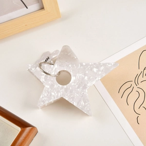 Détail d'un porte-clés étoile texture marbre blanc avec anneau en métal argenté et tag