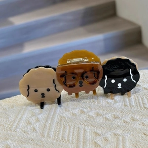 Detailed view of three cute cartoon dog hair claws in beige, brown, and black acetate colors