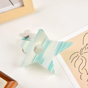 Détail d'une pince à cheveux étoile en acétate à rayures bleues avec décoration florale