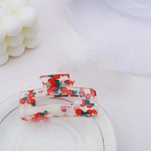 Detail of transparent square hair claw clip featuring red strawberry print and green leaves
