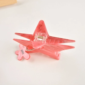 Gros plan sur une pince à cheveux étoile rose marbrée avec un pendentif fleur