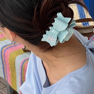 Detail of light blue checkerboard bow hair claw clip with rhinestones worn on head