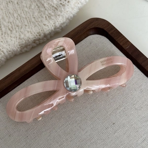 Détail macro d'une pince à cheveux en acétate rose marbré avec strass et logo doré