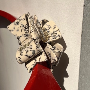 Detailed close-up of a bow-shaped acetate hair claw with rhinestones and marble texture