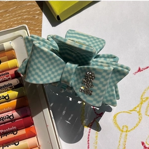 Detail of blue checkerboard acetate hair claw clip with bow shape and rhinestones