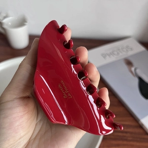 Detail of a burgundy acetate hair claw clip with golden logo and smooth glossy finish