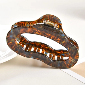 Close-up of a large tortoiseshell hair claw clip with golden metal spring detail