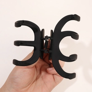 Détail de la grande pince à cheveux pieuvre noire mate tenue à la main pour l'échelle