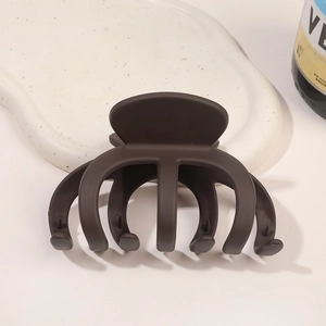 Gros plan d'une pince à cheveux mate marron foncé sur une assiette en céramique