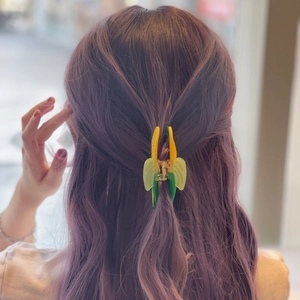 Detailed view of bicolor yellow and green acetate hair claw clip on purple wavy hair