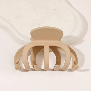 Détail d'une grande pince à cheveux kaki mat posée sur un plateau en céramique blanche