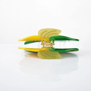Detail view of the yellow and green leaf-shaped hair claw with golden metal spring