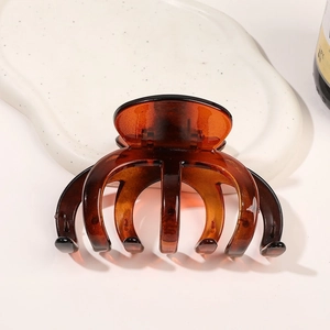 Grande pince à cheveux ambre pour cheveux épais sur une assiette en céramique blanche