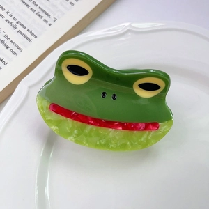 Détails de la pince à cheveux grenouille en marbre vert posée sur une assiette blanche