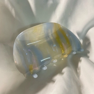 Detailed close-up of semi-transparent shell-shaped acetate hair claw clip with colorful marble pattern