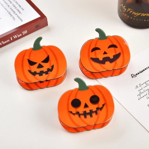 Trois pinces à cheveux citrouilles orange pour Halloween sur un fond esthétique élégant