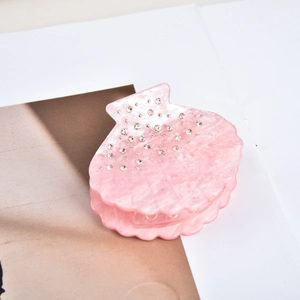 Dettaglio del fermaglio per capelli a conchiglia rosa con strass e finitura marmorizzata