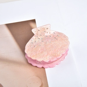 Dettaglio molletta per capelli a conchiglia rosa con glitter e strass scintillanti